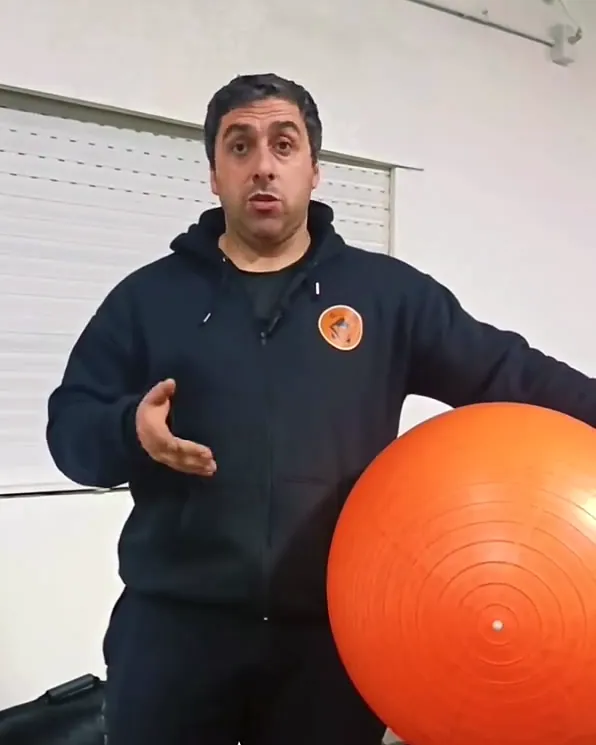 Nicolás Valle con el buzo de Espacio Funcional 25 y una pelota de ejercicio naranja, en el cuartel.